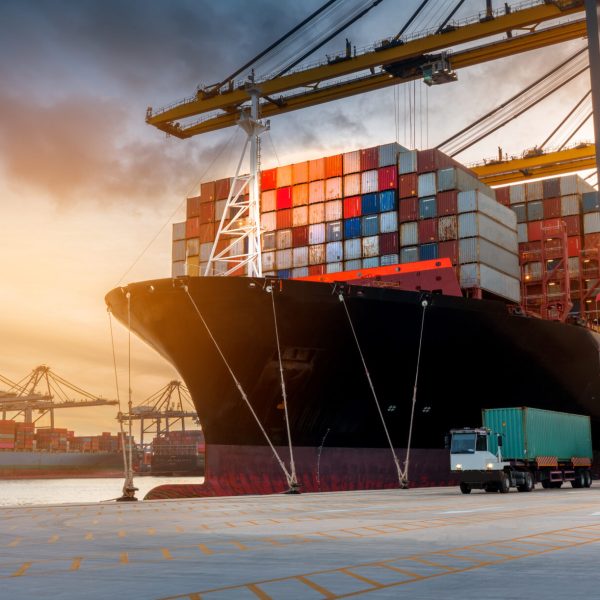 crane loading cargo container from truck to container ship in the international terminal logistic sea port concept freight shipping by ship